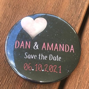 May include: Black round button with a white heart and the text "DAN & AMANDA Save the Date 06.10.2021" in pink.