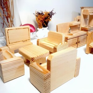 May include: A set of wooden toy furniture for a dollhouse, including a couch, a coffee table, a TV, a chair, and a kitchen set. The furniture is made of natural wood and has a rustic look.