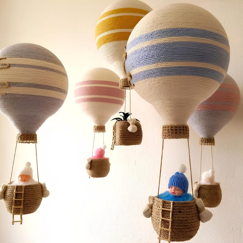 May include: A set of six miniature hot air balloons, each with a different color and pattern. The balloons are made of yarn and have a woven basket underneath. Some of the balloons have small dolls inside the baskets.
