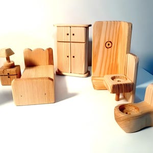 May include: A set of wooden dollhouse furniture, including a bed, a dresser, a nightstand with a lamp, a toilet, and a sink. The furniture is made of unfinished wood and is ready to be painted or stained.