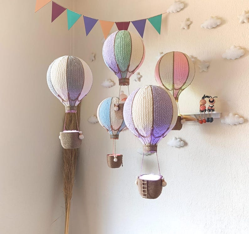 May include: A set of six colourful hot air balloons with baskets hanging from them. The balloons are made of fabric and have a variety of patterns. The baskets are made of woven material and have a rustic look.