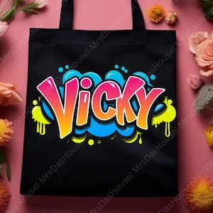 Könnte beinhalten: Schwarze Tragetasche mit dem Namen "Vicky" im Graffiti-Stil. Der Name ist in Pink, Orange und Gelb gehalten, weiß umrandet, mit blauen und gelben Akzenten. Die Tasche hat schwarze Griffe. Ein stilvolles und farbenfrohes Accessoire.