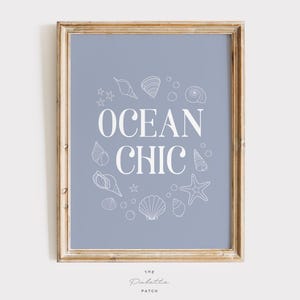 May include: Framed art print with a light blue background and the words "OCEAN CHIC" in white. The text is surrounded by white line drawings of seashells, starfish, and bubbles. The frame is a light brown color.