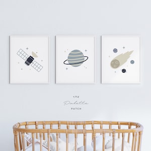 May include: Three framed prints with a space theme. The prints feature a satellite, a planet with rings, and a comet. The prints are white with blue and beige illustrations. The text "The Palette Patch" is printed below the prints.