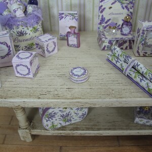 May include: A wooden shelf displaying a collection of lavender-themed items, including boxes, bottles, and rolls of wrapping paper. The shelf is decorated with a lavender floral design.