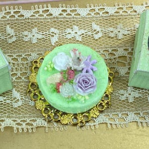 Puppenhaus Miniatur Blumentorte. Französische Miniatur Pattiserie, Cupcakes, Macarons, Meringues. Miniatures-Torte französisches Gebäck. Elegante Bäckerei.