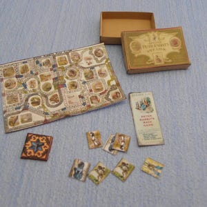 Puede incluir: Un juego de mesa vintage de Peter Rabbit con un tablero de juego colorido, piezas de juego e instrucciones. La caja del juego es marrón con letras doradas y una ilustración de Peter Rabbit.