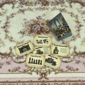 May include: Miniature tabletop game set with cards and a book. The cards feature illustrations of dice, playing cards, chess pieces, and a carriage. The book has a detailed illustration of a room with a person and a carriage.