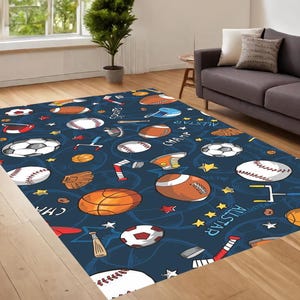 Pu&ograve; includere: Un tappeto blu e bianco a tema sportivo con palline da baseball, pallacanestro, calcio e altre attrezzature sportive. Il tappeto ha le parole "All Star" e "Champ" scritte su di esso.