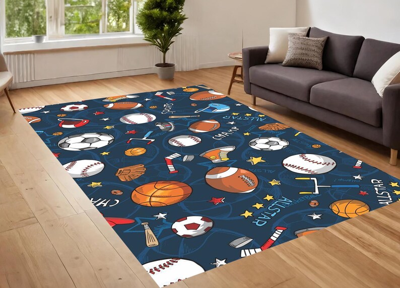 Pu&ograve; includere: Un tappeto blu e bianco a tema sportivo con palline da baseball, pallacanestro, calcio e altre attrezzature sportive. Il tappeto ha le parole "All Star" e "Champ" scritte su di esso.