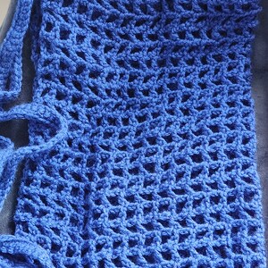 May include: A blue crocheted bag with a square pattern and long straps.