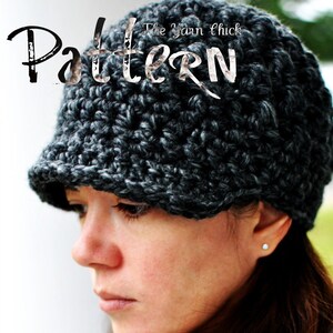 Puede incluir: Un gorro de punto negro y gris con visera. El gorro lo lleva puesto una persona con el pelo castaño y la piel clara. El texto "The Yarn Chick Pattern" es visible en el gorro.