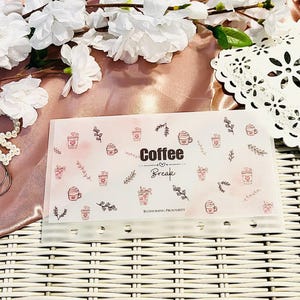 Peut inclure: Un organiseur transparent pour pause-caf&eacute; avec un fond rose aquarelle et des illustrations de tasses &agrave; caf&eacute;. Les mots "Coffee Break" sont imprim&eacute;s en noir. L'organisateur comporte plusieurs trous pour la reliure et est orn&eacute; d'&eacute;l&eacute;ments floraux.