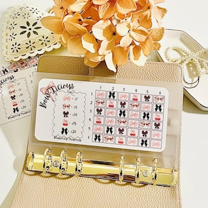 May include: A clear plastic sheet with a grid of colourful bow stickers. The sheet is labelled "Bow Licious" and has numbers 1 to 6 along the top and numbers 1 to 6 along the side. The bows are in various colours, including pink, red, black, and white.