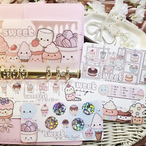 Op de afbeelding: Een roze planner met gouden ringen, gevuld met decoratieve stickers en inlegvellen met schattige illustraties van cupcakes, ijs en macarons. Het woord "sweet" is zichtbaar op verschillende inlegvellen.