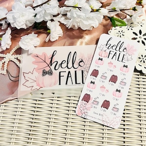 May include: Two decorative cards with a fall theme. One card reads "hello FALL" with a pumpkin and leaf design. The other card features illustrations of pumpkins, sweaters, and coffee cups with prices.