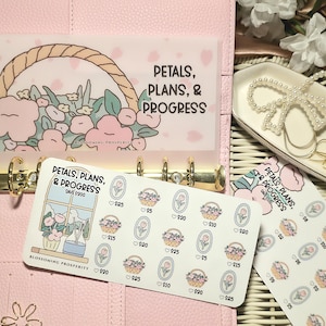Puede incluir: Una agenda rosa con anillos dorados, que contiene un sobre transparente con un diseño de cesta floral y el texto "PETALS, PLANS, & PROGRESS". También se ve una hoja de pegatinas con diseños florales y cantidades en dólares.