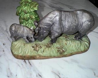 hand-painted porcelain figurine of a  rhino and its calf, with a tree and grassy base