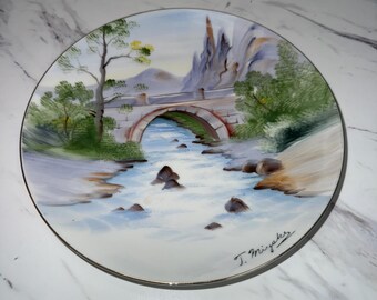 decorative plate featuring a hand-painted landscape scene.