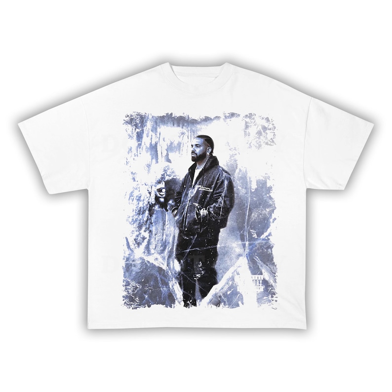 May include: White t-shirt featuring a graphic of a person in a black jacket and pants, set against a blue and white icy background. The design is centered on the shirt.