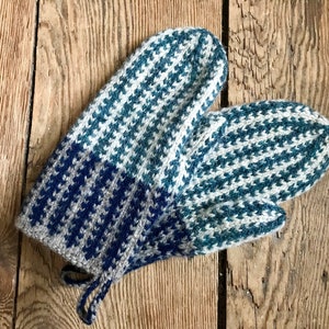 May include: A pair of blue and white knitted mittens with a houndstooth pattern. The mittens have a grey and blue band at the wrist and a long string tie.