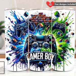 May include: Three white insulated tumblers with a gamer theme. Each tumbler features a controller design with a splash of blue and green paint. The center tumbler has the words "GAMER BOY" in white. The top right corner of the image has the text "12 free designs included".