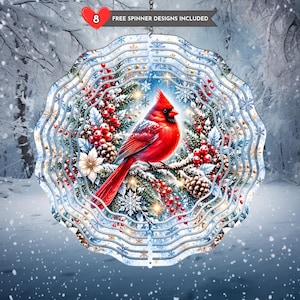 Peut inclure: Un carillon à vent circulaire en métal représentant un cardinal rouge vif perché sur une branche de pin enneigée avec des baies rouges et des pommes de pin. Le motif inclut des flocons bleus et blancs et le texte 8 FREE SPINNER DESIGNS INCLUDED.