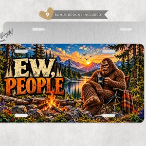 May include: A rectangular metal license plate featuring a graphic of a brown Bigfoot sitting in a camping chair by a campfire, holding a mug. The text reads EW, PEOPLE. The background shows a lake, mountains, and a sunset sky.