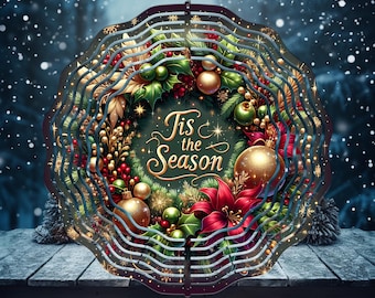 May include: A layered, circular Christmas decoration with a wreath design. The wreath features gold, red, and green ornaments, holly, and the text "Tis the Season". The decoration includes the text "Free Spinner Designs Included".