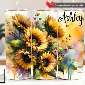 Può includere: Un set di tre bicchieri in acciaio inossidabile con un design ad acquerello di girasoli, farfalle e accenti floreali. Un bicchiere ha il nome "Ashley" in corsivo. È visibile anche il testo "12 free seamless designs included".