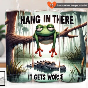 Puede incluir: Un vaso con un diseño humorístico. Presenta una rana de dibujos animados colgando de una rama sobre un caimán, con el texto "HANG IN THERE IT GETS WORSE". Incluye 12 diseños sin costuras gratuitos.