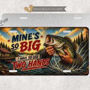 May include: License plate with a fishing theme. The plate features a large-mouth bass held by a person, with the text "MINE'S SO BIG I HAVE TO USE TWO HANDS." The background shows a lake, cabin, and trees.