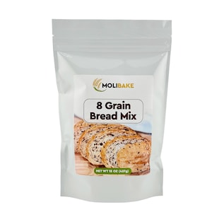 Könnte beinhalten: Ein weißer wiederverschließbarer Beutel mit einem Etikett, auf dem "Molibake 8 Grain Bread Mix" steht. Das Etikett zeigt auch ein Bild von geschnittenem Brot. Der Beutel hat ein Nettogewicht von 15 oz (437 g).