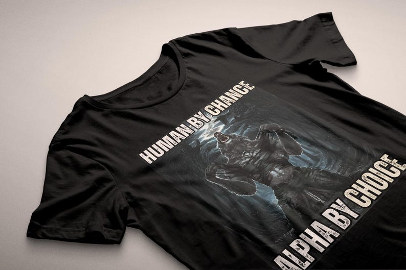 Puede incluir: Camiseta negra con un gr&aacute;fico de lobo y el texto "HUMAN BY CHANCE" y "ALPHA BY CHOICE" en blanco. El lobo se muestra en un entorno oscuro y dram&aacute;tico, con una expresi&oacute;n de aullido.
