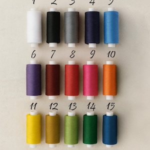 May include: Fifteen spools of thread in various colors, including white, black, gray, navy, and blue. Other colors include purple, red, pink, orange, yellow, green, and teal. Each spool is numbered from 1 to 15.