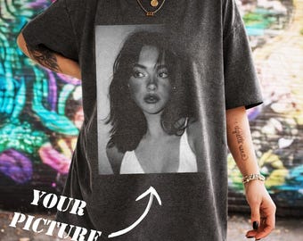 May include: Dark gray t-shirt featuring a black and white portrait of a woman. The shirt has the text "YOUR PICTURE" with an arrow pointing to the portrait. The shirt is oversized and has short sleeves.