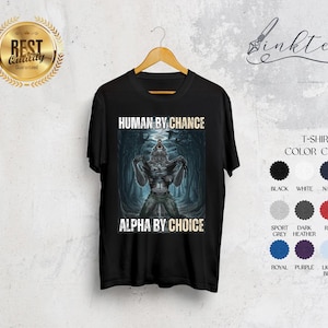 Puede incluir: Camiseta negra con un dise&ntilde;o de hombre lobo. El texto en la camiseta dice "HUMAN BY CHANCE" encima de la imagen y "ALPHA BY CHOICE" debajo. Una carta de colores muestra los colores disponibles.