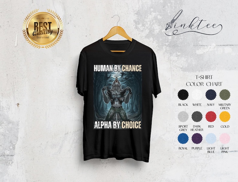 Puede incluir: Camiseta negra con un dise&ntilde;o de hombre lobo. El texto en la camiseta dice "HUMAN BY CHANCE" encima de la imagen y "ALPHA BY CHOICE" debajo. Una carta de colores muestra los colores disponibles.