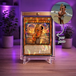 May include: A custom trading card titled Bound By Love encased in a clear acrylic magnetic display stand. The card features a romantic illustration of a couple embracing on a beach at sunset, with game text and stats printed below the image.