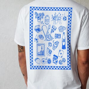May include: White t-shirt with a blue checkered border and a blue graphic print on the back. The print features various illustrations, including a laptop, beer can, pizza slice, and a watch. The shirt is a casual, everyday wear item.