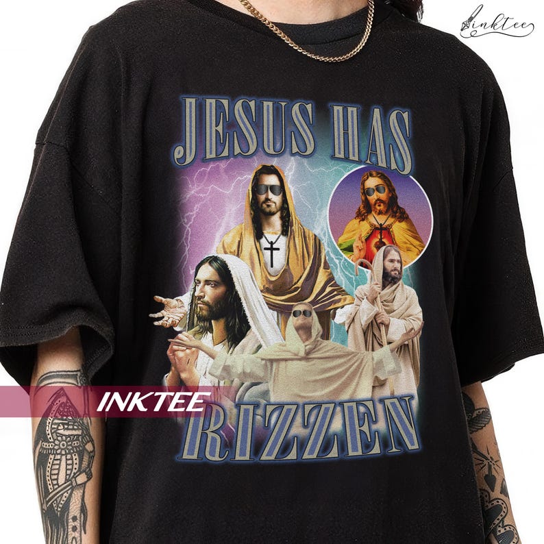 May include: Black t-shirt with a graphic design featuring multiple images of Jesus wearing sunglasses, a cross pendant, and the text "JESUS HAS RIZZEN" in a blue and purple font. The design includes lightning bolts and a circular image.