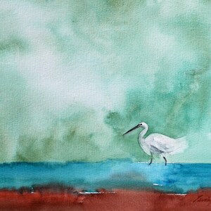 Puede incluir: Una pintura de acuarela de una garceta blanca de pie en un cuerpo de agua azul. El fondo es de un verde suave con nubes blancas.