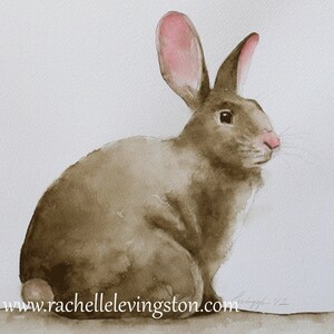 May include: Watercolor painting of a brown rabbit with pink ears sitting on a white background. The rabbit is looking to the right of the image. The artist's signature is visible in the bottom right corner.