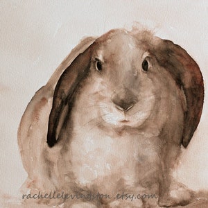 May include: Watercolour painting of a brown rabbit with large floppy ears. The rabbit is looking directly at the viewer with a curious expression. The painting is done in shades of brown and beige.