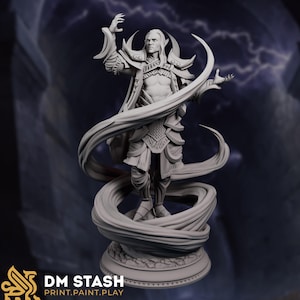 Puede incluir: Una figura gris impresa en 3D de un personaje de fantasía masculino con orejas puntiagudas, armadura ornamentada y tela fluida. La figura está posando con los brazos extendidos, y la base tiene el texto "DM STASH PRINT.PAINT.PLAY."