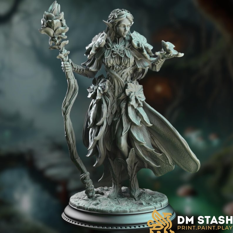 Front-facing render of the Feywalker miniature, a graceful fae spellcaster adorned in layered leaf robes and crowned with petals. She holds a gnarled staff with blooming flowers and extends one hand in a gesture of magic.