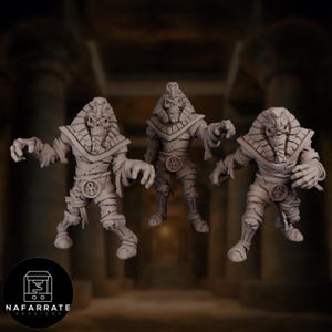 May include: Three beige mummy figurines with detailed wrappings and pharaoh-style headdresses. Each figure has outstretched arms and an ankh symbol on the chest. The figures are set against a blurred background with pillars and a logo that reads "NAFARRATE 3D DESIGNS."