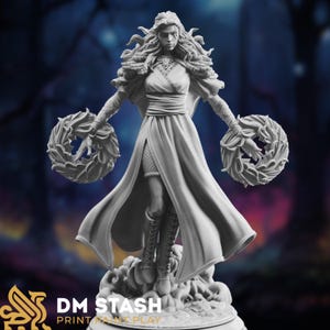 Könnte beinhalten: Eine weiß bemalte Miniaturfigur einer Frau mit langen, fließenden Haaren, die eine lange Robe trägt und zwei Kränze in ihren Händen hält. Die Figur steht auf einem Sockel mit einem wolkenartigen Design.
