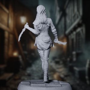 Rear view of female rogue miniature with long hair and tight-fitting leather armor, daggers raised as she moves down a cobbled street.