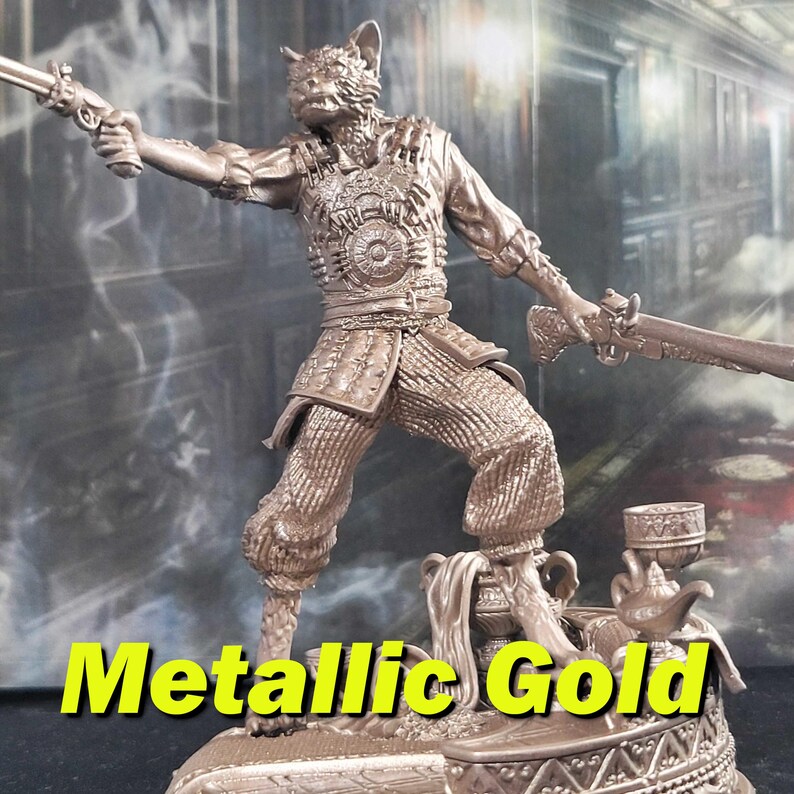 K&ouml;nnte beinhalten: Eine Figur aus metallischem Gold, die eine katzenartige Kreatur darstellt, die in der einen Hand eine Pistole und in der anderen ein Schwert h&auml;lt. Die Figur steht auf einem dekorativen Sockel mit einer Teekanne und einer Tasse.